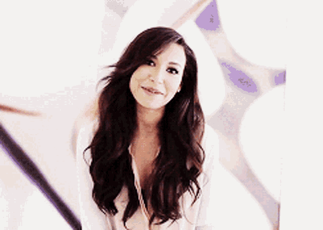a woman with long brown hair is smiling in front of a white background