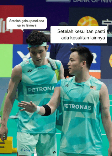 two badminton players wearing petronas jerseys are talking