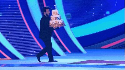 a man in a suit is carrying a cake that says ' a ' on it