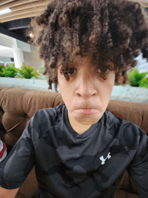 a young boy with curly hair wearing a black under armour shirt