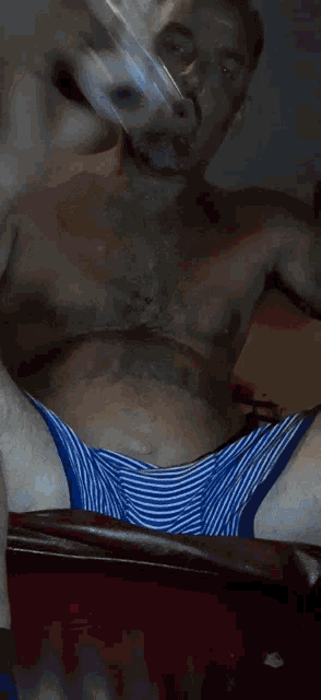 a shirtless man in blue and white striped underwear is blowing smoke into the air