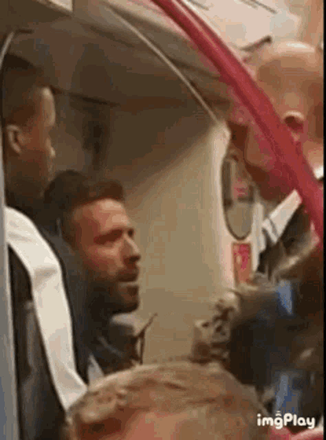 a man is talking to another man on a train .