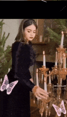 a woman in a black dress is putting candles in a candle holder .