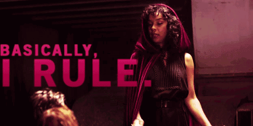 a woman in a red cape is standing in front of a sign that says basically i rule