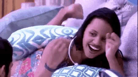 a woman is laying on a bed next to a man and laughing .