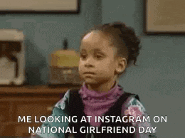 a little girl is sitting in a room looking at a picture of herself on instagram on national girlfriend day .