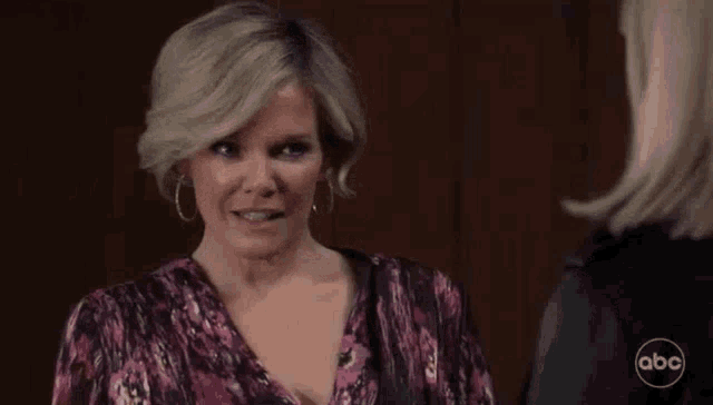 a woman is pointing at another woman 's chest while talking to her .