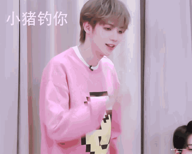 a boy wearing a pink sweater with the letter m on the front