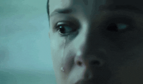 a close up of a woman 's face in a dark room looking at something .