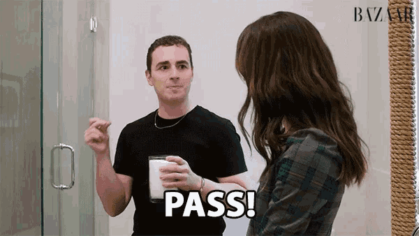 a man in a black shirt holds a glass of milk while a woman says pass