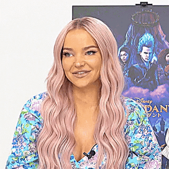 a woman with pink hair is standing in front of a poster for disney 's descendants