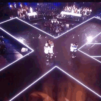 a group of people are dancing on a stage in a dark room