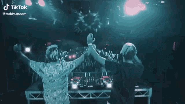 two dj 's on stage with their hands in the air and a tiktok watermark