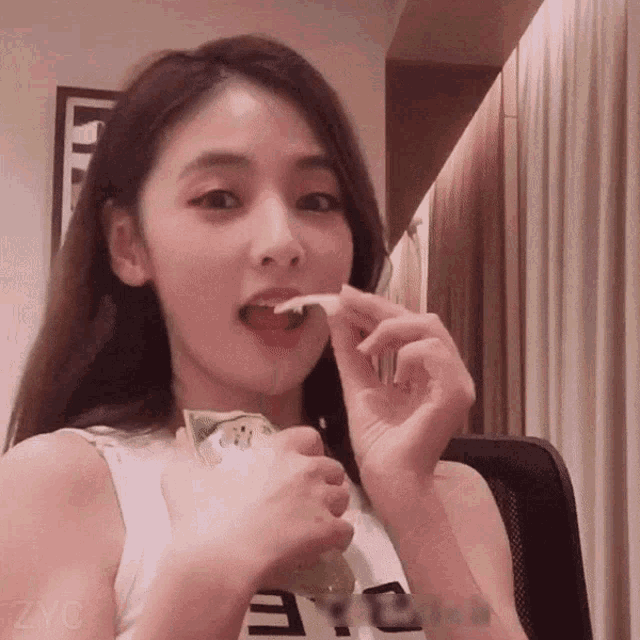 a woman is eating a piece of food with zyc written in the corner