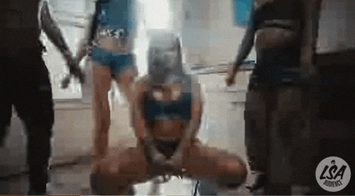 a group of people are dancing in a room with a woman wearing a mask on her head .
