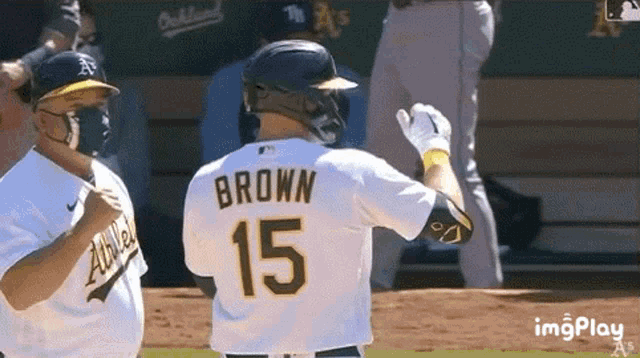 a baseball player with the number 15 on his jersey is standing on the field .