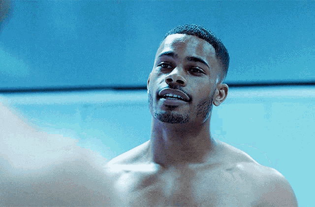 a shirtless man with a beard is looking at something