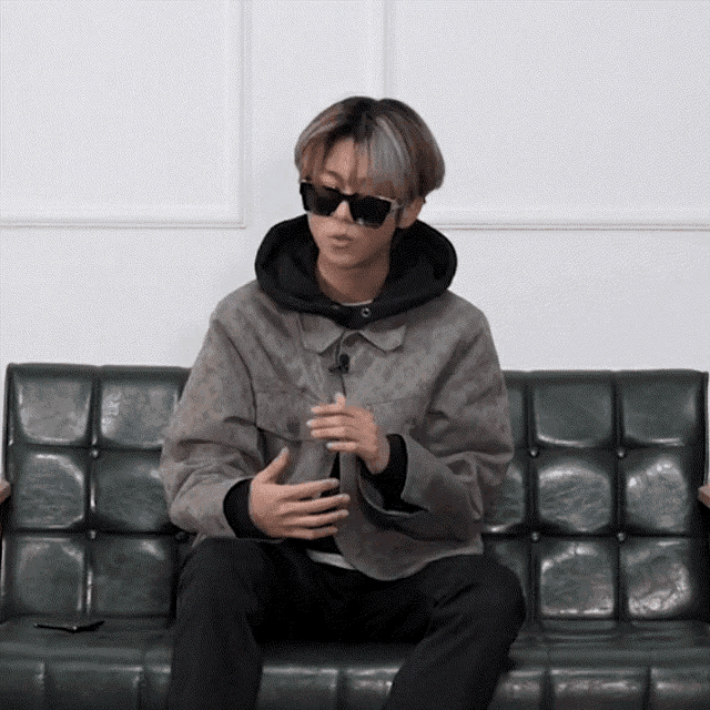 a man wearing sunglasses sits on a couch