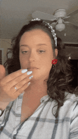 a woman wearing a headband and red earrings is applying makeup to her lips