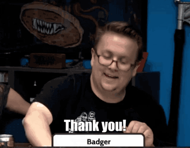 a man sitting at a table with a sign that says thank you badger