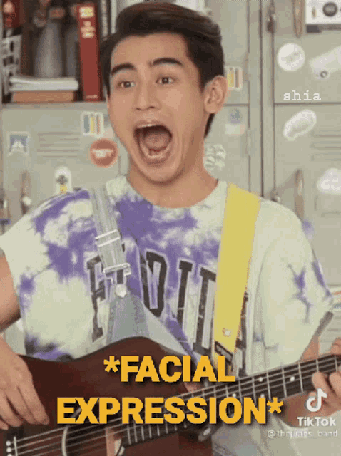 a young man playing a guitar with a facial expression on his face