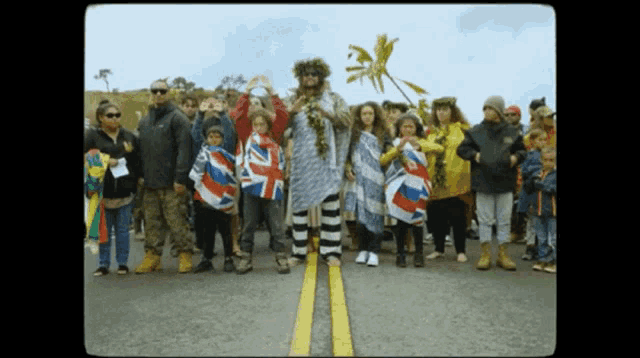 a group of people standing on the side of a road holding flags one of which says ' uk ' on it