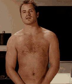a shirtless man is standing in front of a television with his hands in his pockets .