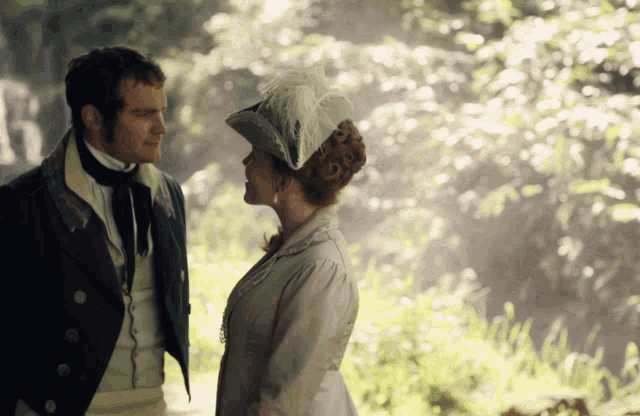a man and a woman are looking at each other in a forest