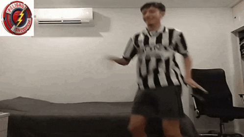 a man in a striped shirt is dancing in front of a peligro sign