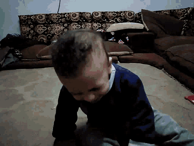 a baby in a blue shirt is crawling on the floor