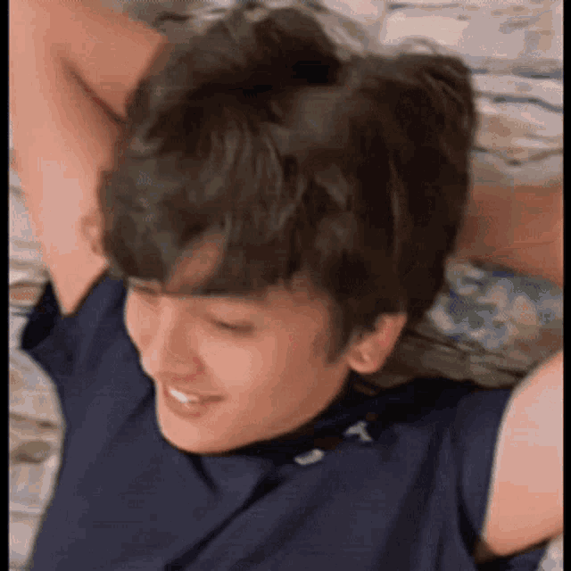 a young boy is laying on a bed with his arms outstretched