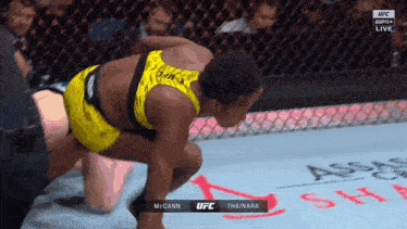 a woman in a yellow top is kneeling down in a boxing ring