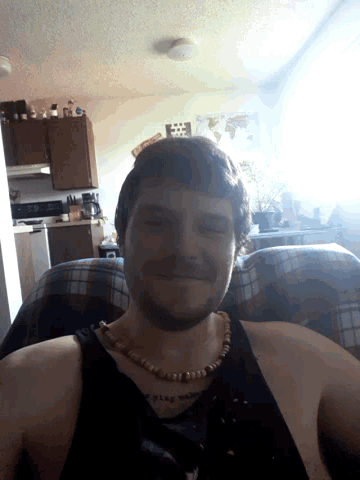 a man wearing a necklace is sitting in a chair