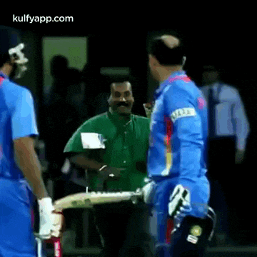a group of cricket players are standing next to each other and talking .