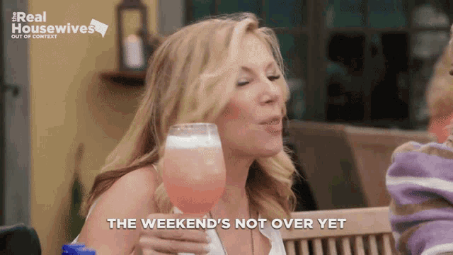 a woman drinking from a glass with the words " the weekend 's not over yet " on the bottom