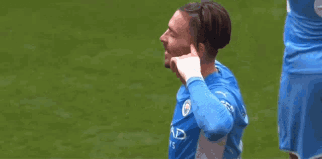 a soccer player wearing a blue shirt is holding his fist to his face .