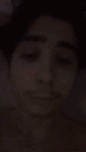a close up of a young man 's face with his eyes closed and a mustache .
