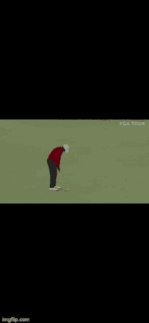 a man in a red shirt is holding a golf club while standing next to another man on a golf course .