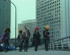 a group of people with mohawks are walking down a street in front of tall buildings