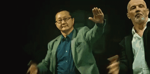 two men are standing next to each other in a dark room and dancing .