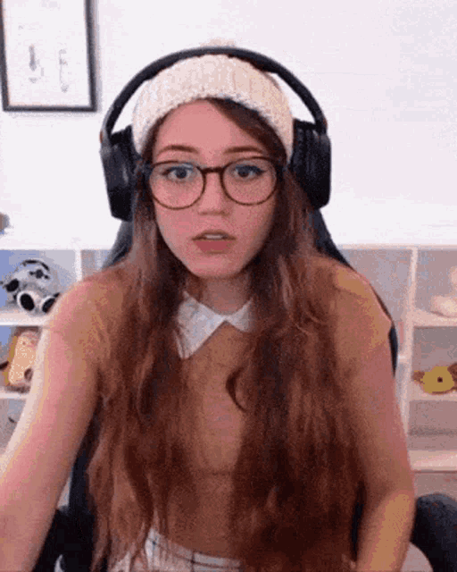 a woman wearing glasses and headphones is sitting in a chair and making a funny face .