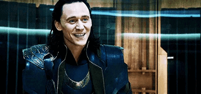 loki from avengers : age of ultron is smiling and looking at the camera in a dark room .