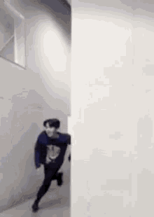 a man is running down a hallway between two walls .