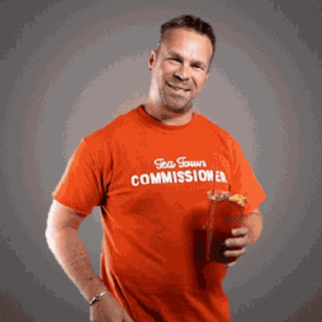 a man wearing an orange shirt that says tea forum commissioner
