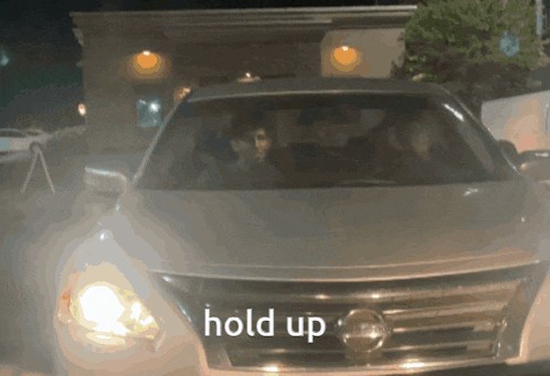 a nissan car is parked in front of a building that says hold up