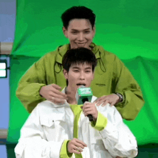 two men are standing next to each other in front of a green screen .