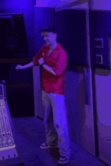 a person in a red shirt is standing in a dark room with a purple light behind them