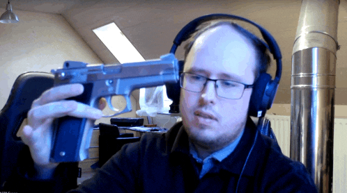 a man wearing headphones is holding a gun in his hand