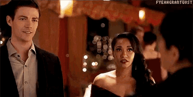 a man and a woman are standing next to each other in a room and talking to each other .