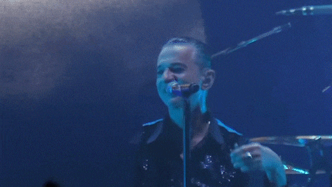 a man singing into a microphone with a crowd behind him
